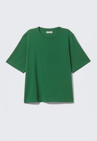 T-shirt verde in cotone a maniche corte con scollatura rotonda e vestibilità rilassata. Presenta un orlo che si ferma all'hip, una texture liscia e nessuna decorazione aggiuntiva.