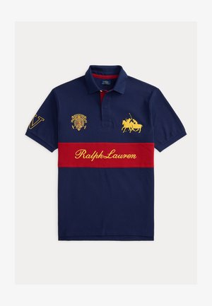 Granatowa koszulka polo z czerwoną poziomą linią, żółtym napisem Ralph Lauren, haftowanym logo gracza polo oraz herbem na piersi i rękawie.