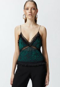 Zelena prozirna bluzica s crnim čipkastim detaljima, naborima i dizajnom s V-izrezom. Sadrži točkaste uzorke i podesive naramenice.