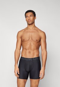 Black boxer briefs made of smooth fabric, featuring a snug fit and a waistband with embossed "AMOUR UN" lettering in contrasting color.