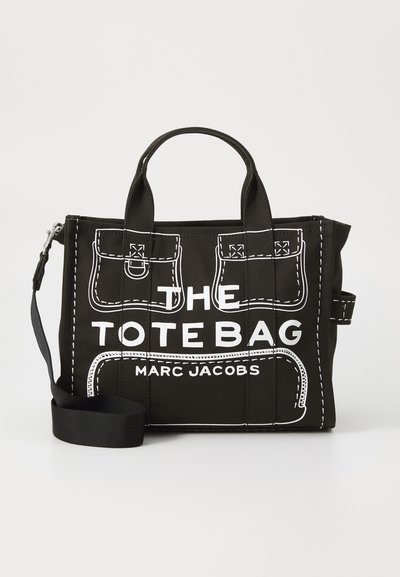 Bolso tote negro con detalles de costura blanca, que cuenta con bolsillos, asas superiores y una correa de hombro extraíble. En el frontal se muestra "THE TOTE BAG" y "MARC JACOBS."