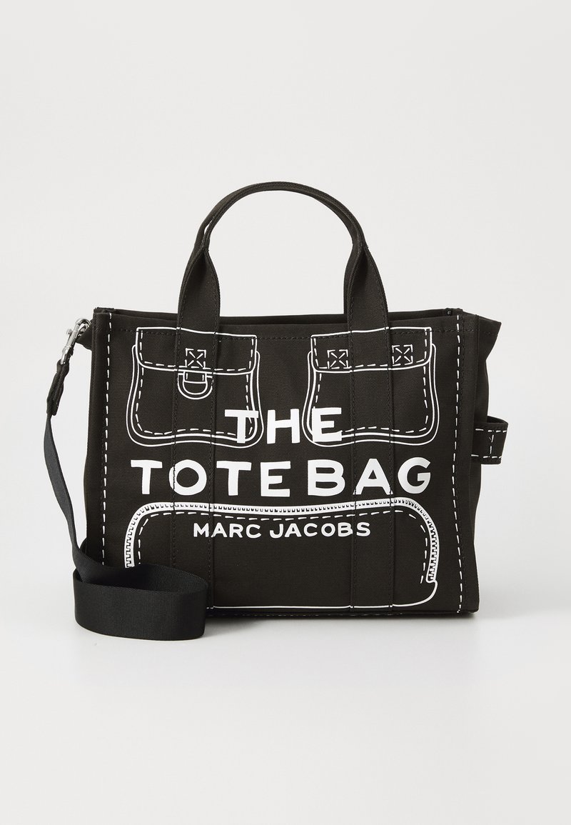 Saco tote preto com detalhes brancos costurados, apresentando bolsos, alças superiores e uma alça de ombro removível. Na frente exibe "THE TOTE BAG" e "MARC JACOBS."