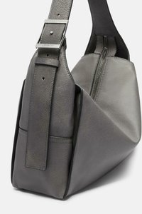 Borsa in pelle grigia con una forma geometrica unica. Presenta una superficie texturizzata, una larga tracolla con una fibbia metallica e una chiusura zip superiore.