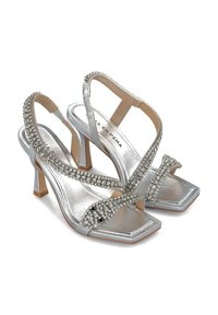 Sandale argintii cu toc înalt, cu curele încrucișate, embellisate cu strasuri, vârf pătrat și un toc modest. Finisaj cu luciu metalic.