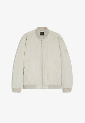 Vaaleanbeige bombarintakki, jossa etuvetoketju, kaksi nepparilla suljettavaa taskua, resorikaulus, -hihansuut ja -helma sekä "BOSS"-logo kaulanauhassa ja vasemmassa hihassa.