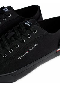 Czarne płócienne sneakersy z sznurowanym zapięciem, metalowymi oczkami i logo w czerwono-biało-niebieskich akcentach po boku.