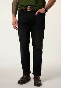 Jeans de mezclilla negra con corte recto, con un ligero desgaste y diseño de cinco bolsillos, combinados con botas de cuero marrón y un cinturón marrón.