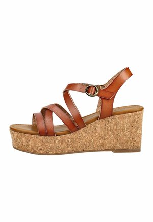 Brązowy skórzany sandał na koturnie z trzema paskami z przodu, paskiem wokół kostki z okrągłą klamrą oraz podeszwą na platformie o strukturze korka.
