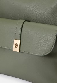Bolso de piel texturizada verde con cierre de solapa, que presenta un clasp de hardware dorado y un sutil detalle de costura a lo largo de los bordes.