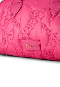 Quiltet pink taske med blomsterbroderi, prydet med en guldlogo og en glat overflade. Accenter inkluderer afrundede ører og en sikker lukning.