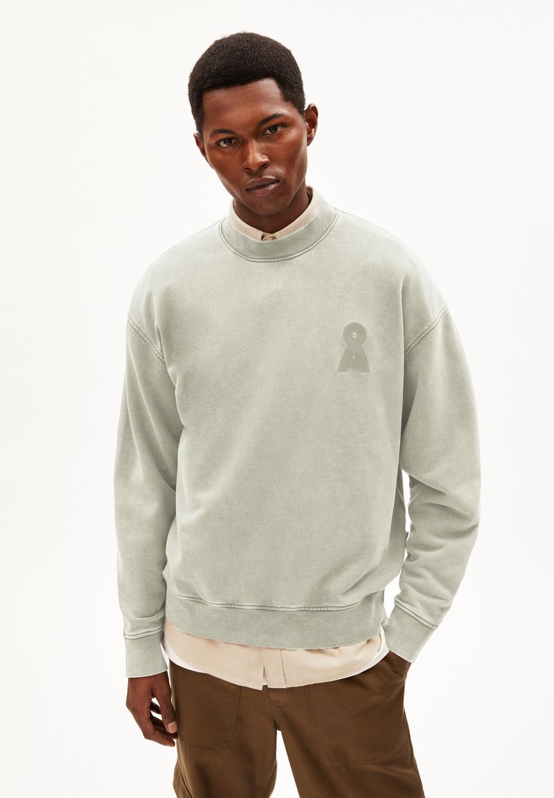 Lange groene sweatshirt van zacht materiaal, met een ronde halslijn, geribbelde manchetten en een subtiele sleuteloog logo op de borst.