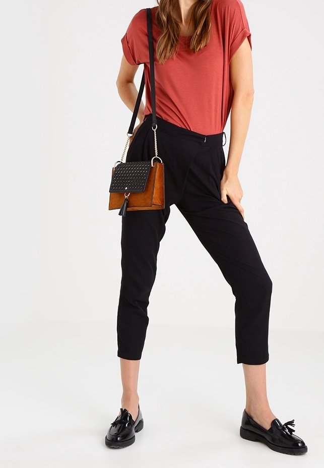 Pantaloni neri a vita alta, maglietta rossa e mocassini neri, con una borsa a tracolla marrone e nera dotata di una patta testurizzata e di una tracolla a catena.