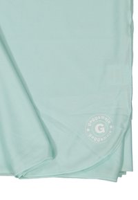 Vaaleansininen kangas, jossa on teksturoitu pinta, ja siinä on pyöreä logo, jossa on "G" ja brändin nimi. Kangas on taitettu siististi.