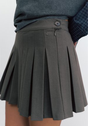 Tamnosiva plisirana suknja sa bočnim patentnim zatvaračem i gumbom, nošena uz tamnosivi top ubačen unutra.