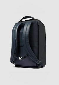 Marineblauwe leren rugzak met een gestructureerde vorm, verstelbare gevoerde bandjes, een handvat aan de bovenkant en een ritsvak voor opslag.