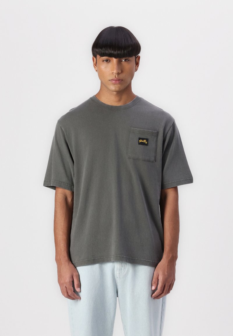 Gray cotton t-shirt with a round neck and short sleeves, featuring a visible left chest pocket and yellow branding detail.