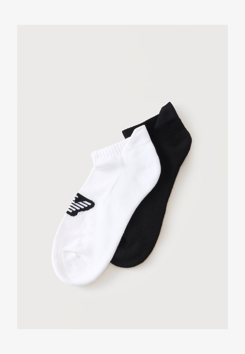 Deux chaussettes basses, une blanche avec un logo noir et une noire unie, posées sur un fond clair.