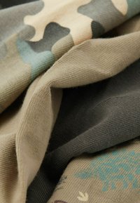 Textiles con un patrón de camuflaje en tonos beige, verde y gris, con una textura suave, que presentan diversos diseños, incluyendo motivos de animales.