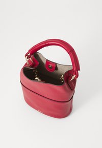 Sac à main en cuir rouge de forme ronde, avec une courte poignée et un fermoir à bouton pression doré. L'intérieur est doté d'un revêtement doux et d'un porte-clés attaché.