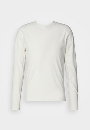 Pikkade varrukatega särk kreemvalgest puuvillast, millel on ümar kaelus ja sile, pehme tekstuur ilma nähtavate mustrite või aktsentideta.