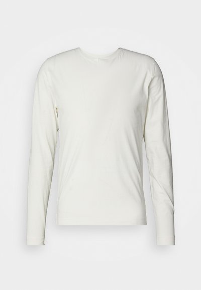 Μακρυμάνικη μπλούζα σε εκρού βαμβάκι, με κρουαζέ λαιμό και λεία, απαλό υφή χωρίς ορατά σχέδια ή λεπτομέρειες.