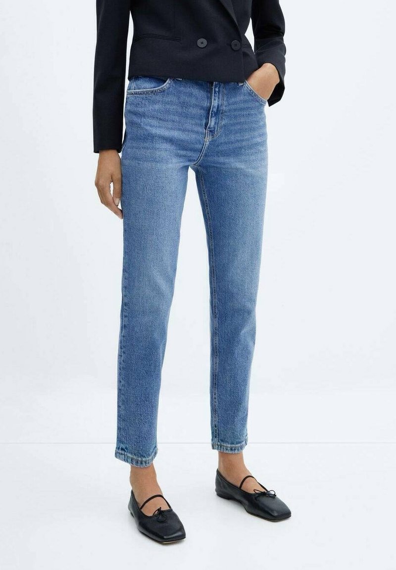 Vaqueros de mezclilla azul claro con corte recto, talle alto y un sutil desgaste, combinados con bailarinas negras y un blazer negro.