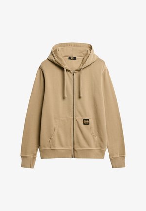 Beige zip-up hættetrøje lavet af blødt stof, med en frontlomme, ribbede manchetter og et mærke på venstre lomme. Hætte med snøre.