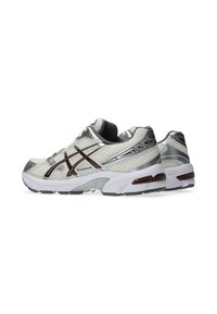 Buty sportowe w kolorach szarym, białym i srebrnym. Siatkowa tkanina, wyściełana podeszwa, wyraźny system sznurowania oraz detal z logo po boku.