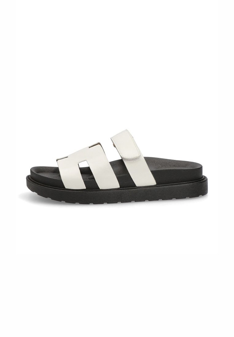 Sandalias blancas de deslizamiento con dos correas anchas y una suela texturizada negra. Las correas tienen un acabado suave y cierre de Velcro.