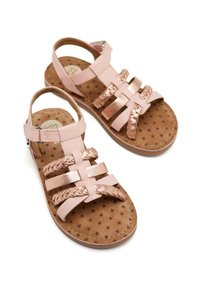 Sandalias de cuero rosa con acentos dorados, que cuentan con tiras trenzadas, un diseño de punta abierta y una suela marrón texturizada con patrones de estrellas.