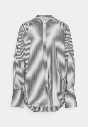 Chemise à manches longues avec des rayures verticales noires et blanches, un col haut et de larges poignets sur fond blanc.