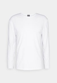 Camiseta blanca de manga larga fabricada en suave algodón, con un cuello redondo y un corte recto sencillo sin patrones ni acentos visibles.