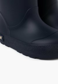 Bottes de pluie en caoutchouc marine avec un extérieur texturé, une tige lisse et une semelle à motifs. Conception légère avec un petit logo sur le côté.