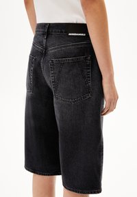 Zwarte denim shorts met een relaxte pasvorm, voorzien van achterzakken, subtiele vervaging en een merklabel op de tailleband.