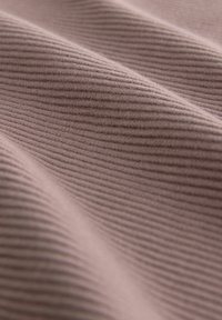 Tejido texturizado en un suave tono malva, con sutiles rayas verticales que crean una apariencia de olas en la superficie.