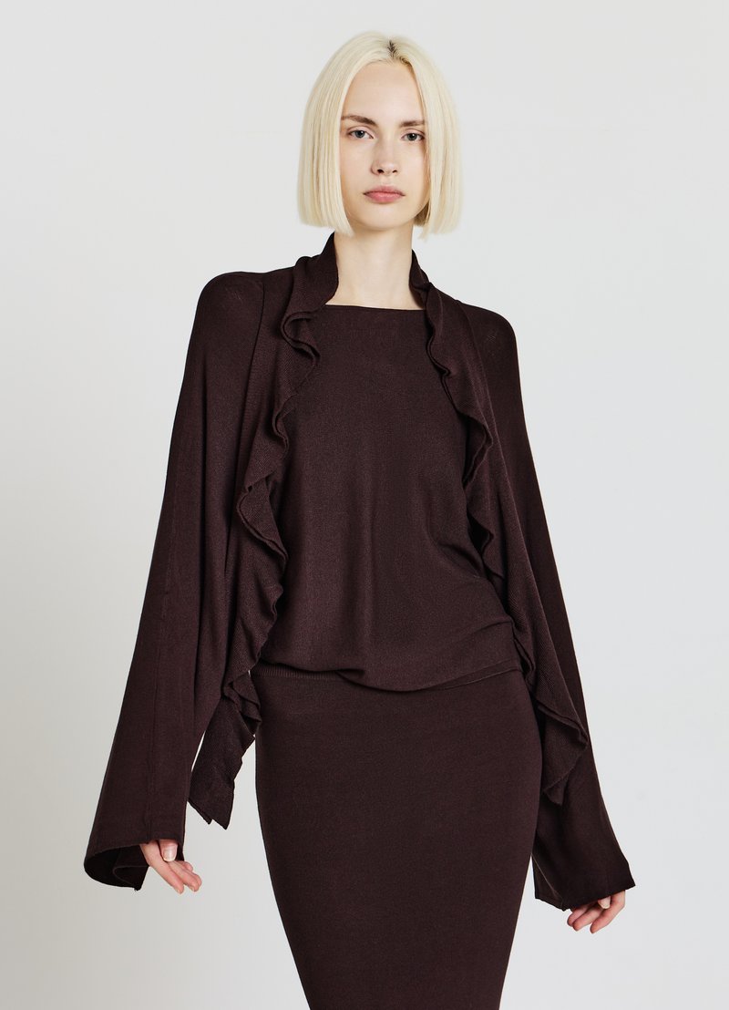 Brown textured knit top layered with a ruffled shawl collar and long sleeves, paired with a matching fitted skirt, both in a rich brown hue.
