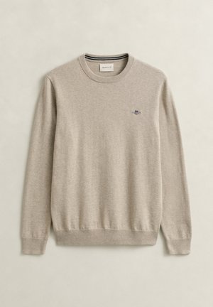 Beige sweater met ronde hals, lange mouwen, geribbelde manchetten en zoom, en een klein geborduurd logo op de linkerborst.