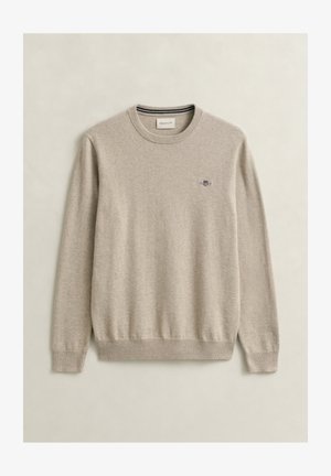 Beige sweater met ronde hals, lange mouwen, geribbelde manchetten en zoom, en een klein geborduurd logo op de linkerborst.