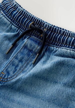 Vaaleansiniset farkkushortsit, joissa on joustava vyötärönauha, tummansininen nyöri ja brodeerattu yksityiskohta. Sisältää etutaskun ja sileän pinnan.