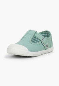 Zapatilla de lona verde menta con una tira elástica, suela de goma blanca y forro de cuadros. Presenta un detalle decorativo de botón plateado.