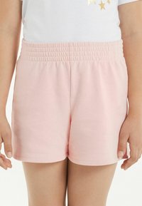 Pantaloni corti rosa chiaro con vita arricciata elastica, materiale in cotone morbido e un design semplice e minimalista senza ulteriori motivi o dettagli.