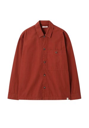 Chemise à manches longues rouge rouille avec boutons, poche poitrine et col, présentée à plat sur fond blanc.