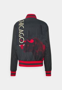 Sort bomberjakke med røde accenter, der har "CHICAGO" tekst og et grafisk billede af en tyr. Ribbet manchetter og kant, glat tekstur.