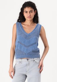 Blauwe gebreide mouwloze top met een diepe V-hals, open structuur met een chevron patroon, textuurdetails en een aansluitende zoom.