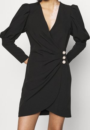 Czarna sukienka kopertowa z długimi rękawami, głębokim dekoltem w serek i marszczonym bokiem. Posiada trzy ozdobne guziki w talii oraz gładką fakturę materiału.