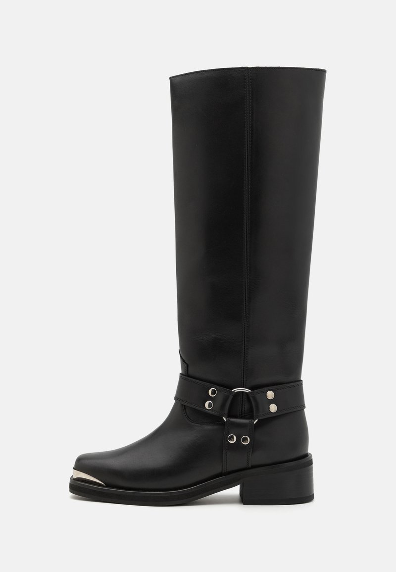 Botas de cuero negras hasta la rodilla con punta redondeada, tapa de punta plateada y una correa ajustable con acentos metálicos. Diseño de tacón cuadrado.