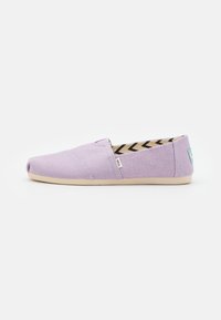 Scarpa slip-on in tela lilla con pannelli laterali elastici, suola beige e interno a motivo con zig-zag neri e crema, etichettata TOMS.