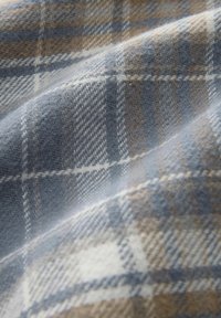 Mėlynos ir smėlio spalvos languota medžiaga su minkšta tekstūra, su tinklelio raštu ir subtiliomis zigzaginėmis detalėmis.