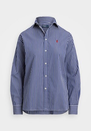 Chemise à manches longues avec rayures verticales bleues et blanches, boutonnée, avec col et logo rouge brodé sur la poitrine gauche.