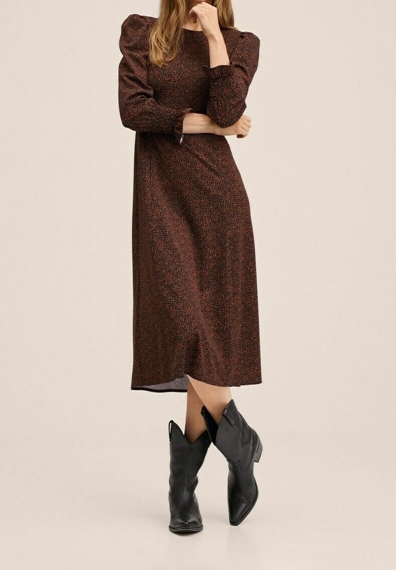 Braunes knielanges Kleid mit kurzen Puffärmeln und strukturiertem Muster. Kombiniert mit schwarzen Cowboy-Stiefeln und einem glatten Stofffinish.